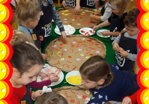 Dzieci tworzą pizze z materiałów plastycznych.